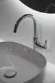 Waschtischarmatur von Ideal Standard mit chromfarbener Oberfläche, einem hohen Bogen und einem Handhebel zur Steuerung des Wasserflusses, montiert über einem ovalen Waschbecken.